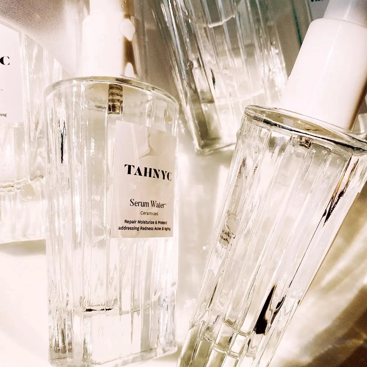Clear skincare bottles with 'TAHYC' branding on a light background