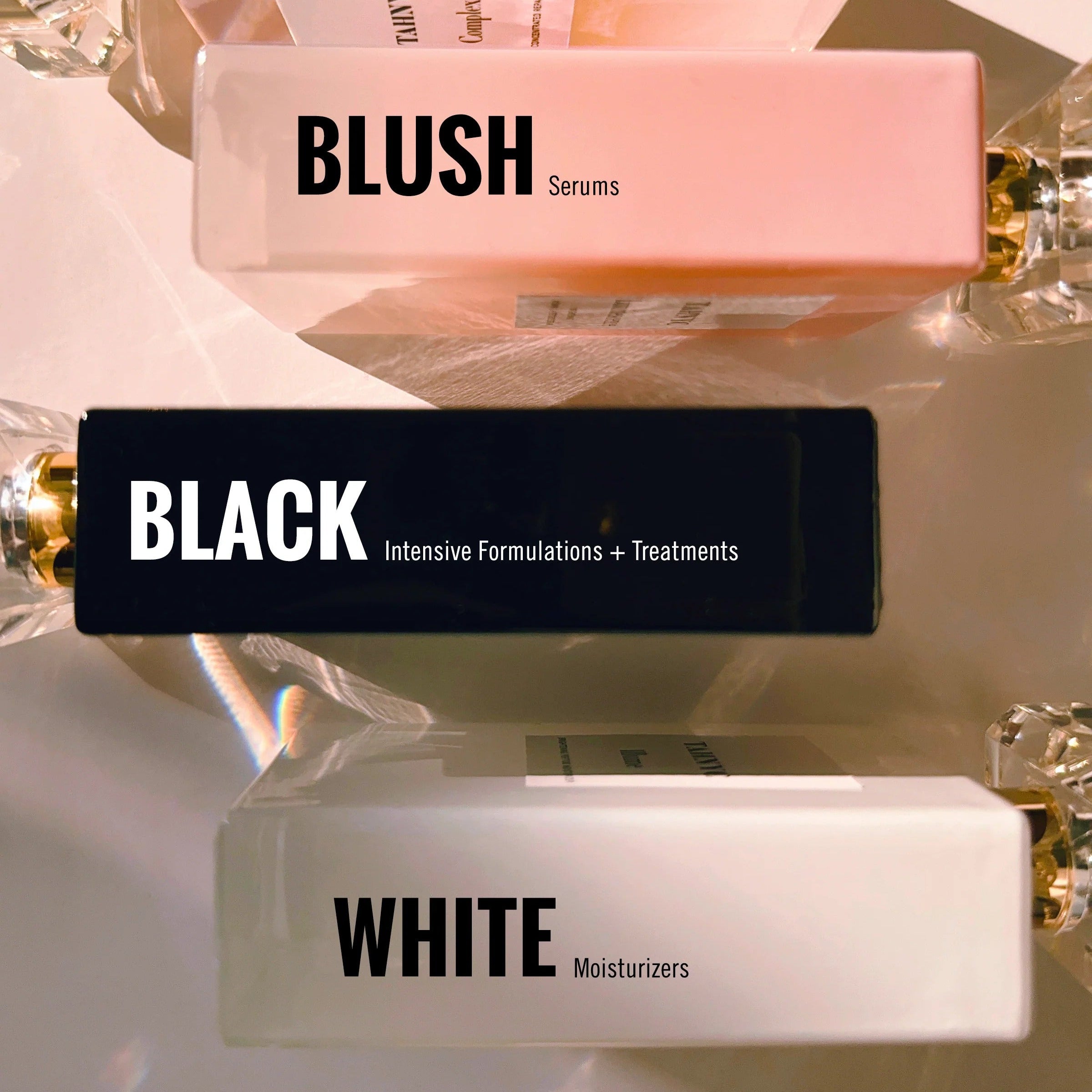 Flat-lay of TAHNYC Blush, Black, and White serum bottles arranged in a row showcasing the brand’s product lines.