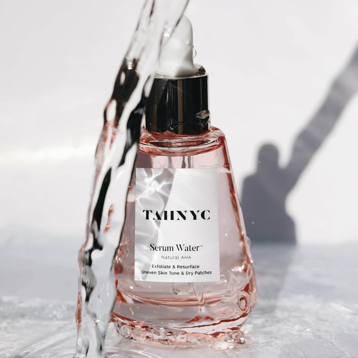 TWINNC serum water bottle with liquid being poured over it on a light background