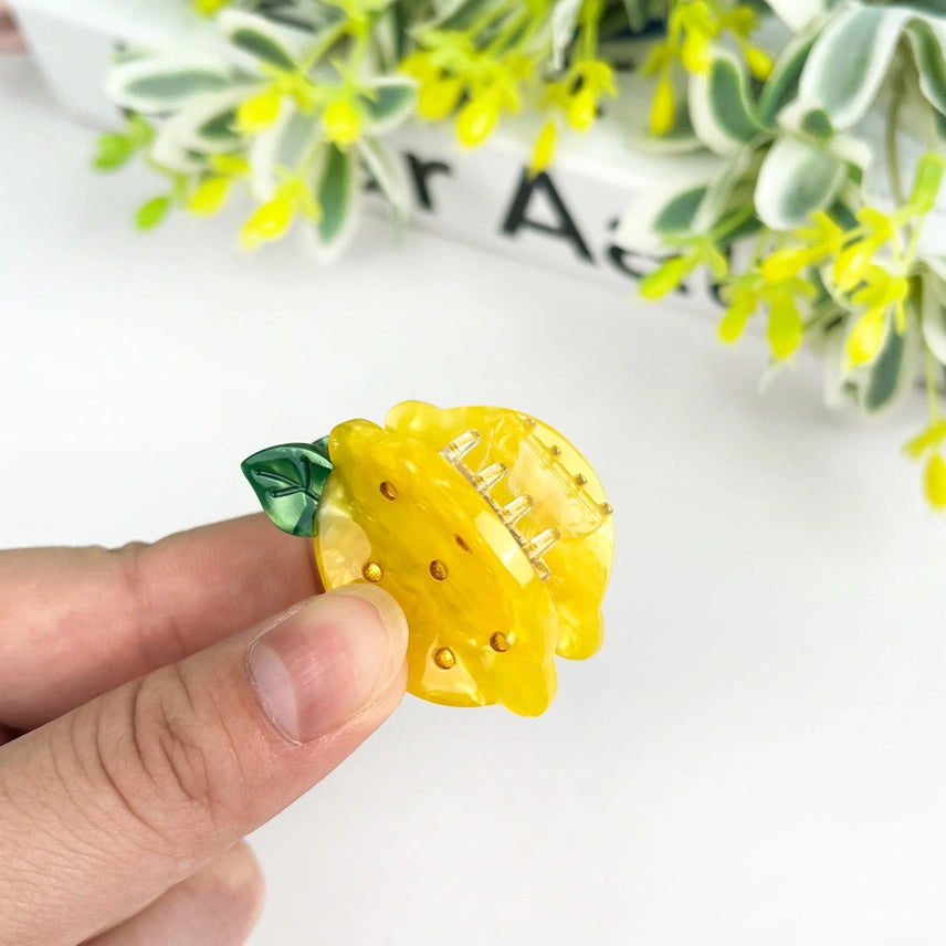 Yellow lemon-shaped object with a green stem on a white background