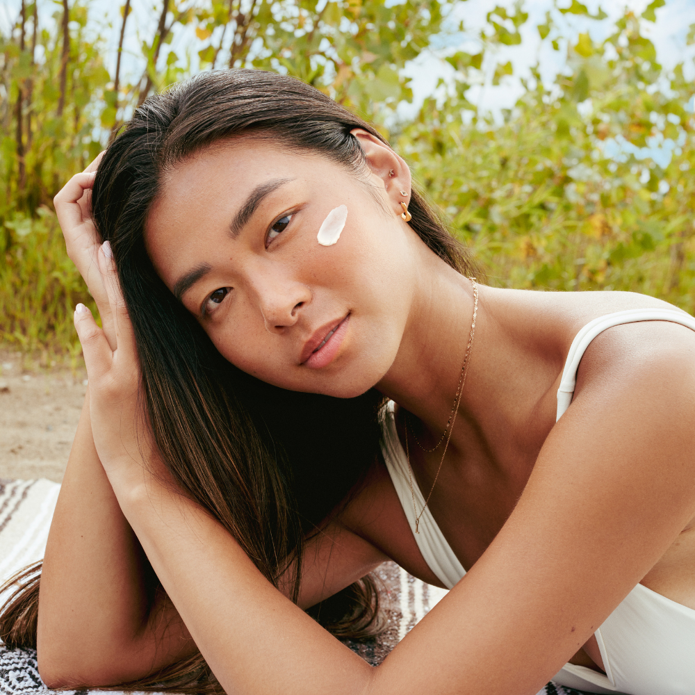 Woman lying on a blanket outdoors with greenery in the background