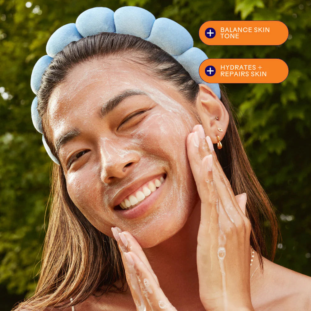 Woman applying skincare product with text indicating benefits on a blurred green background