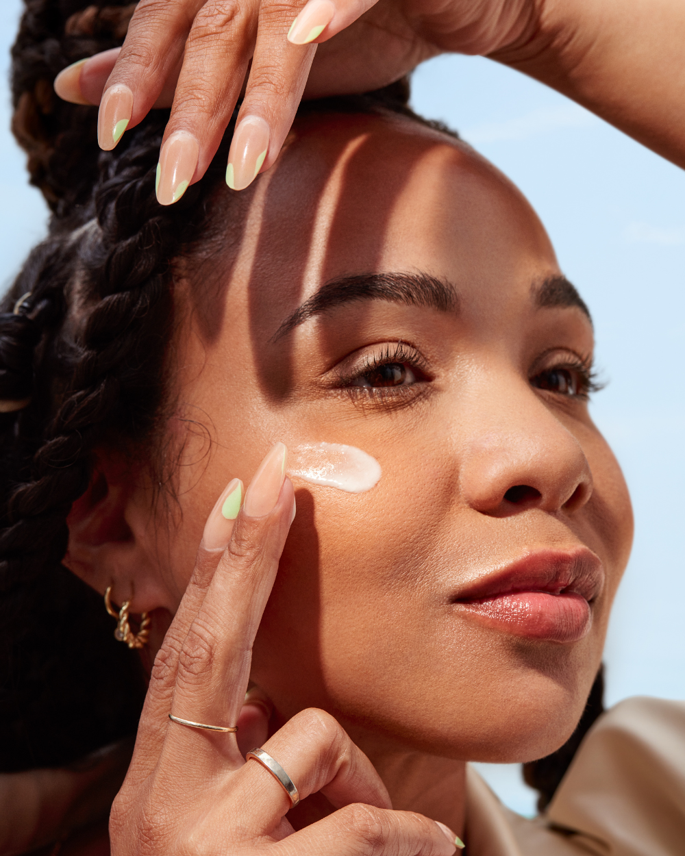Woman applying sunscreen to her face with a clear cream.