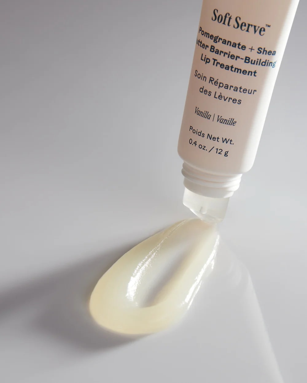 Tube of Soft Serve lip treatment with a smear of product on a white background