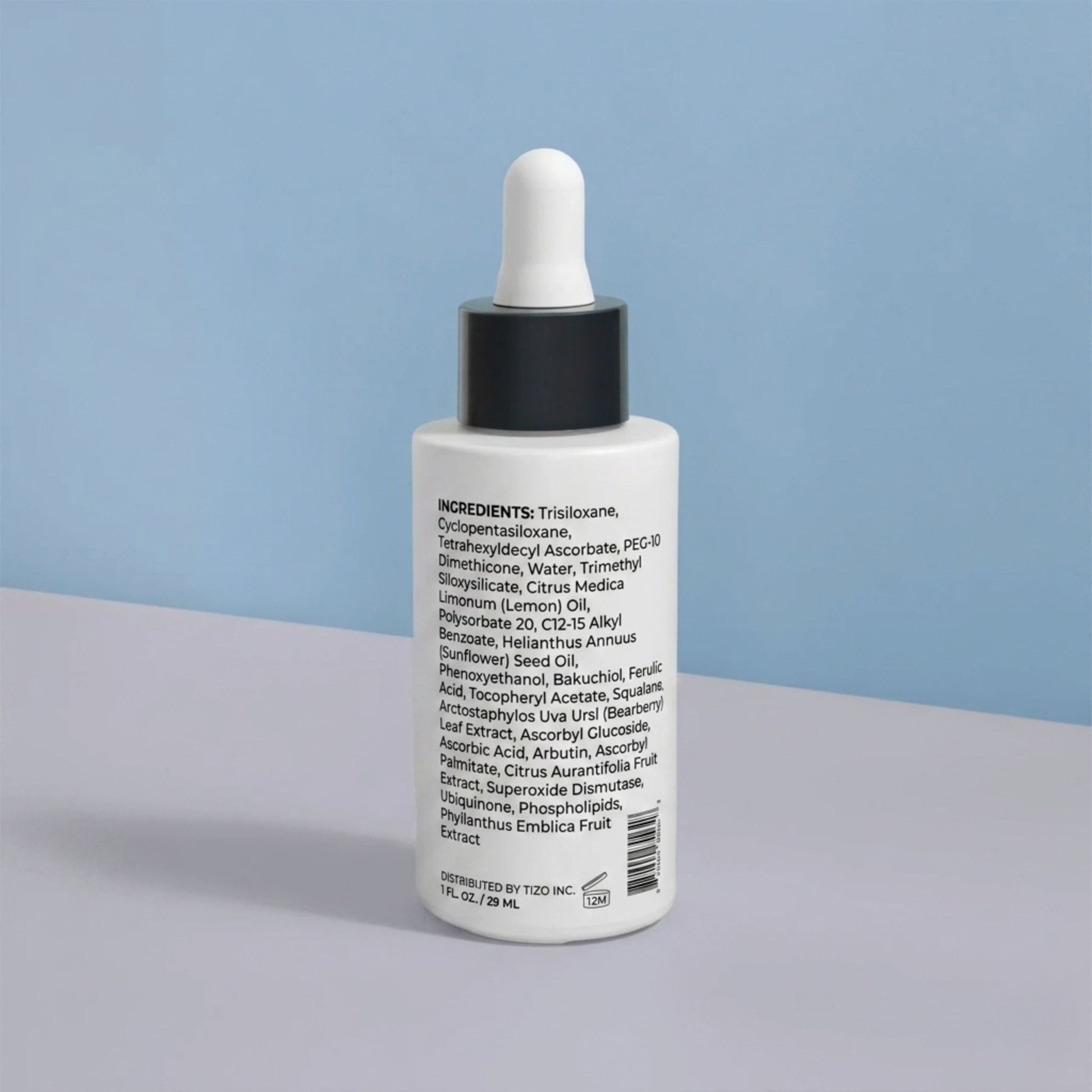 Skincare dropper bottle with visible ingredient list on a gray surface and light blue background