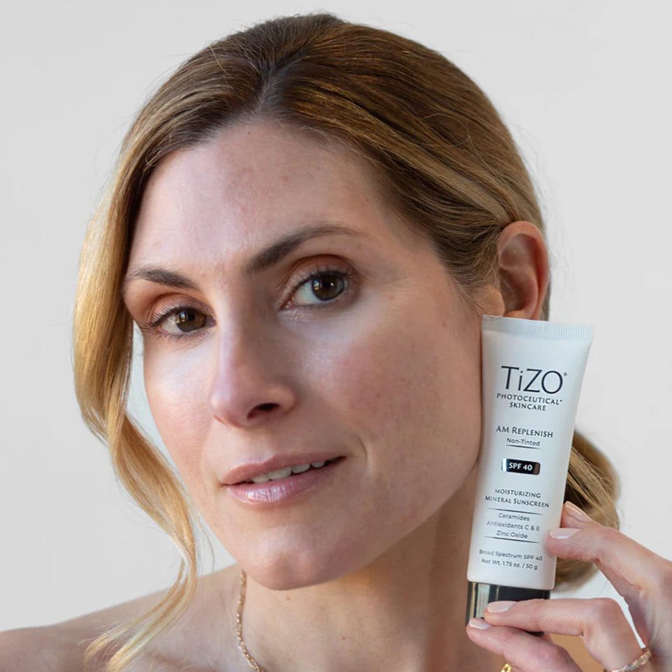 Woman holding a Tizo skincare product against a plain background