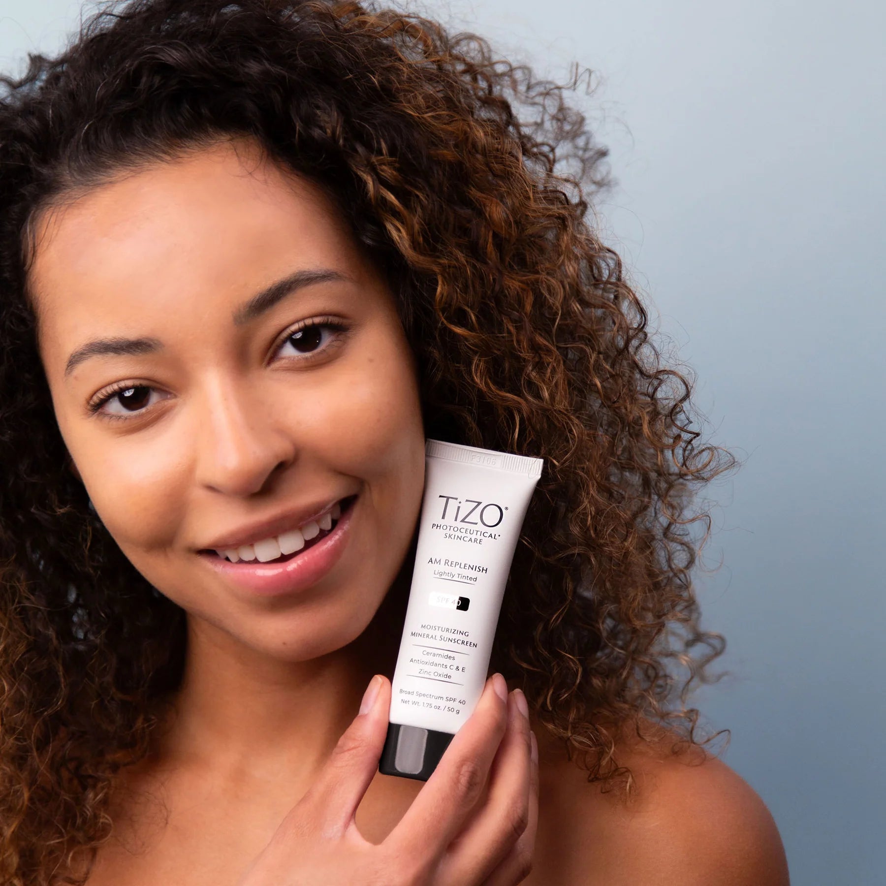 Woman holding a Tizo product against a neutral background