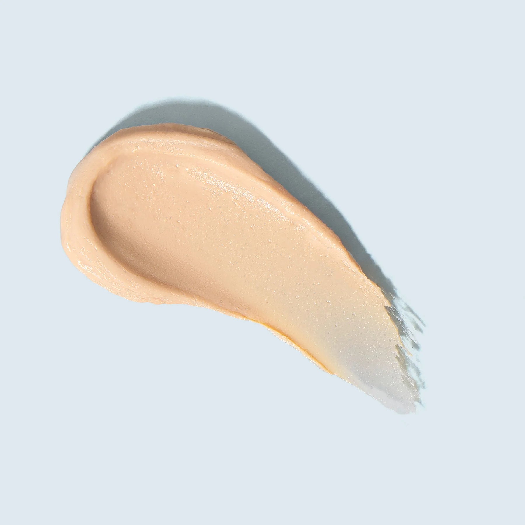 Swatch of beige cream on a light blue background