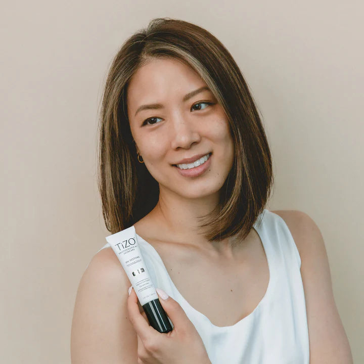 Woman holding a Tizo hair product against a plain background