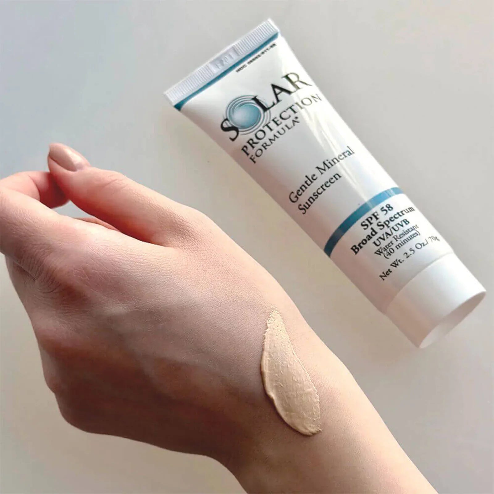 Tube of Solar Protection Formula sunscreen on a hand with a swatch applied.