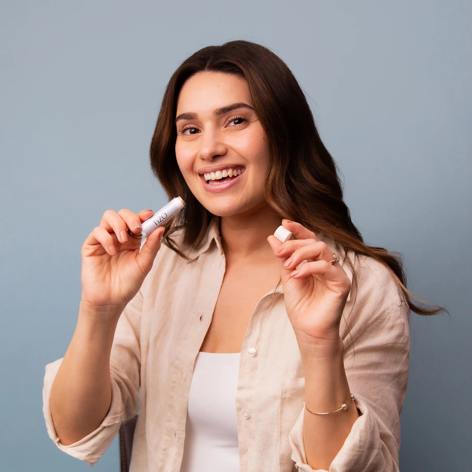 Woman holding two small white containers against a gray background