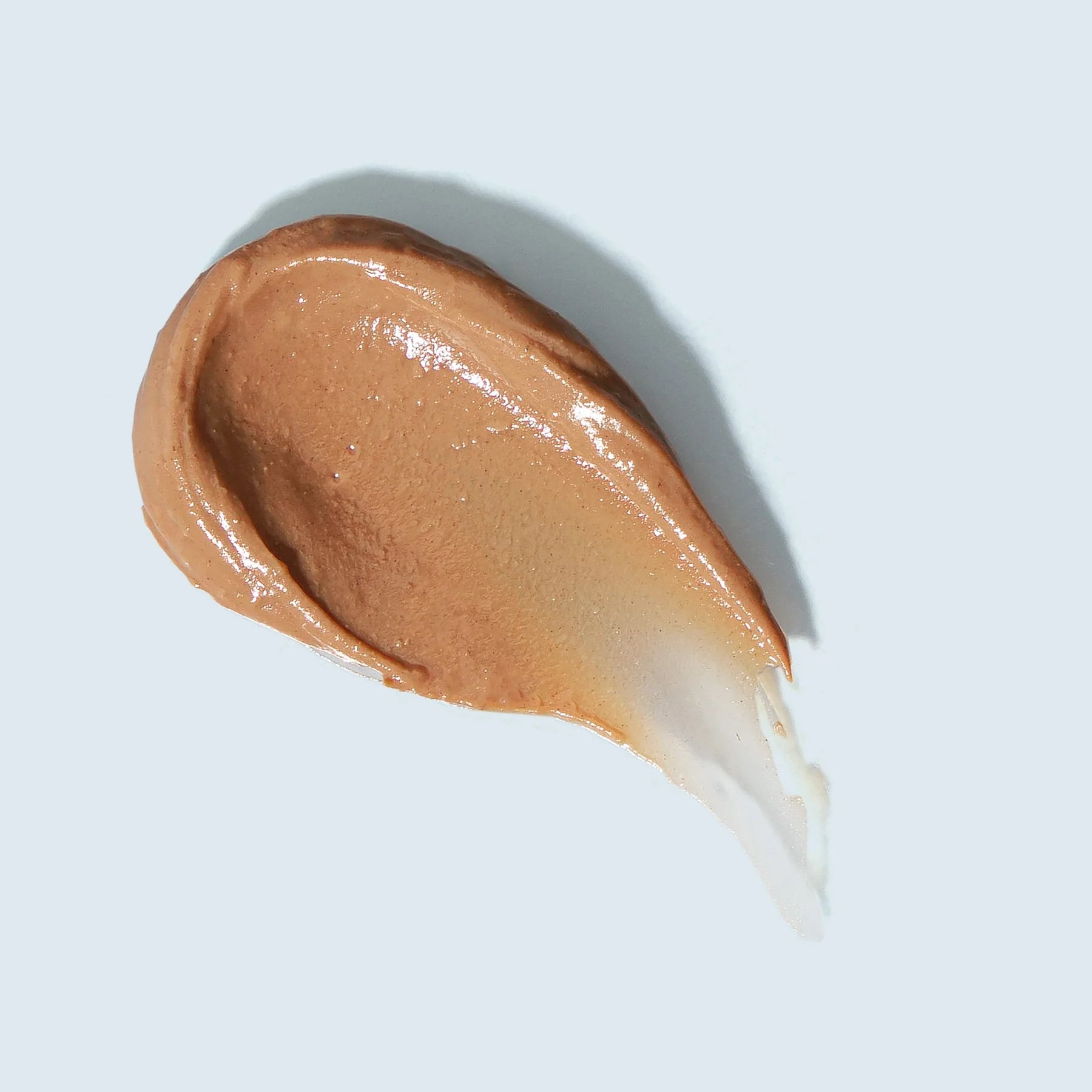 Brown cosmetic cream swatch on a light gray background