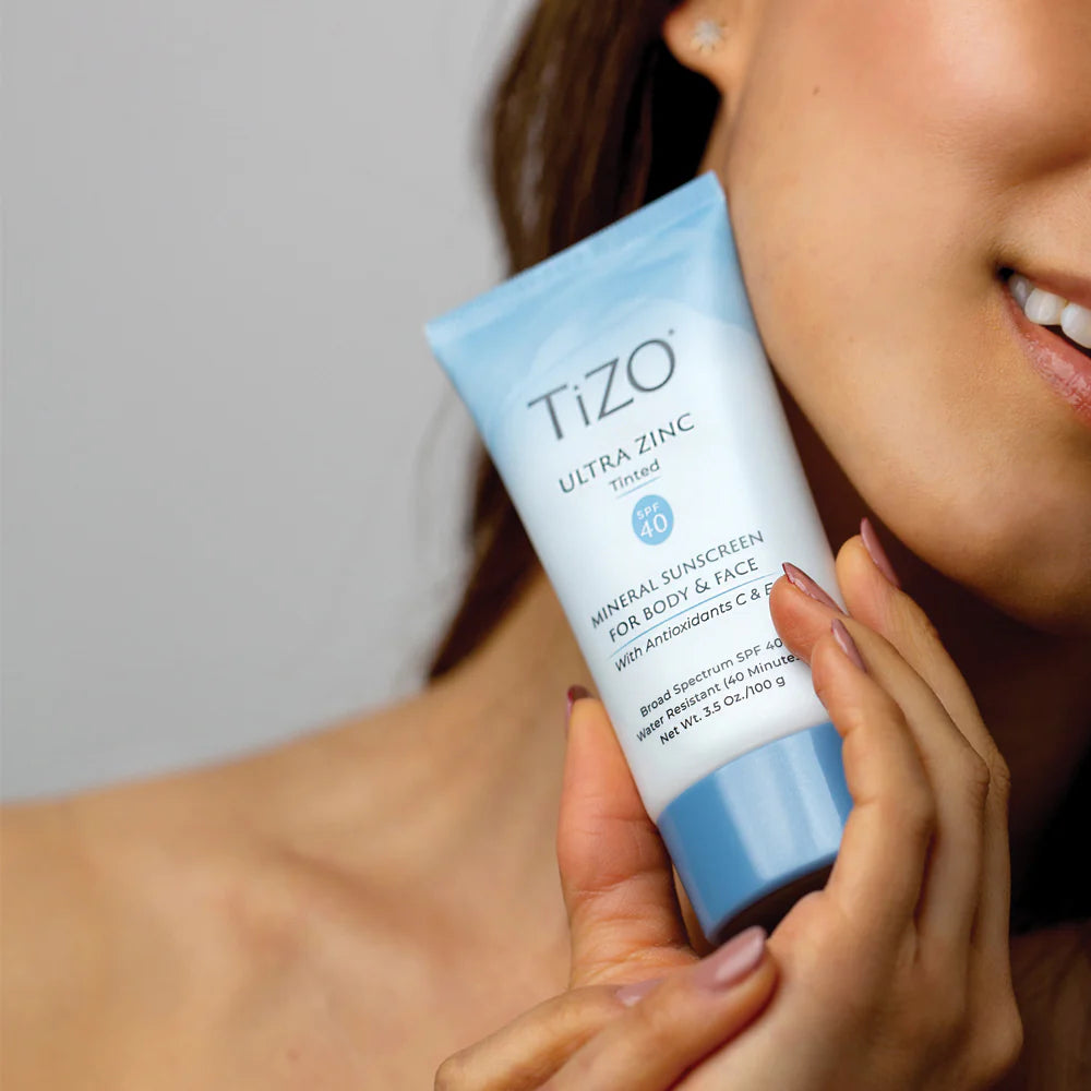 Person holding a TIZO Ultra Zinc sunscreen tube close to their face.