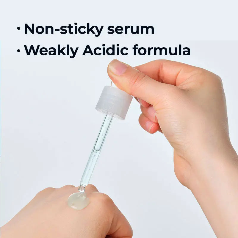 Hand holding a dropper with clear liquid against a light gray background