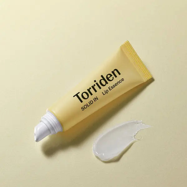 Torriden lip essence tube with a swatch of product on a beige background