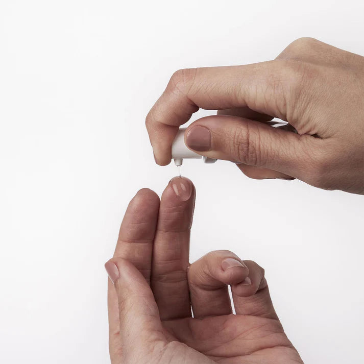 Close-up of hands holding a small white object against a light background