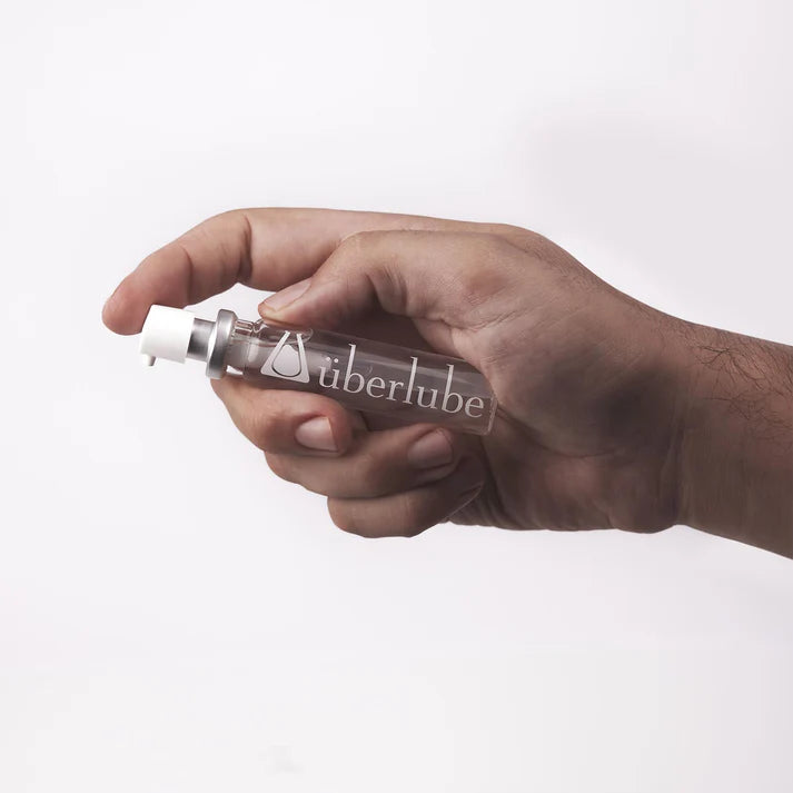 Hand holding a bottle of Uberlube against a white background