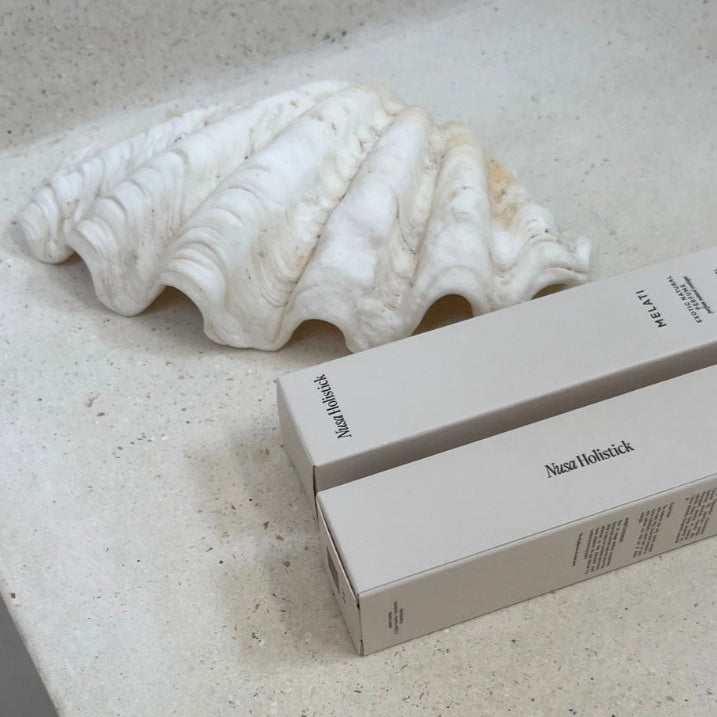 Nuxe box on a textured surface with a shell in the background