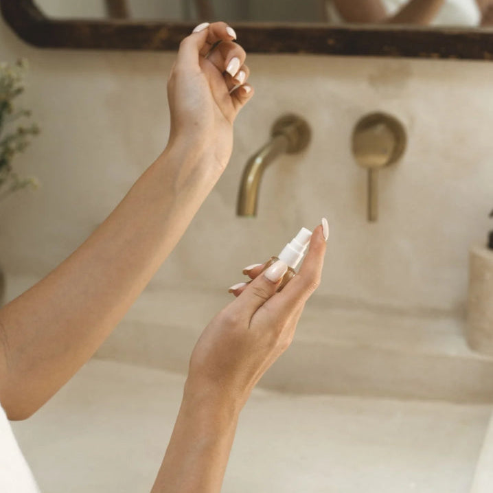 Person applying cream to their hand in front of a mirror in a bathroom.