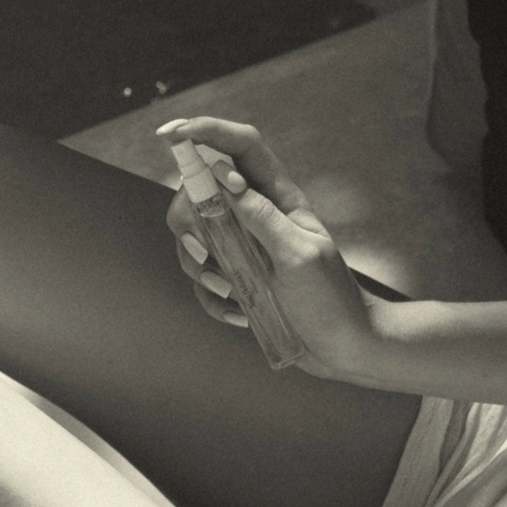 Person applying a product to their arm with a spray bottle.