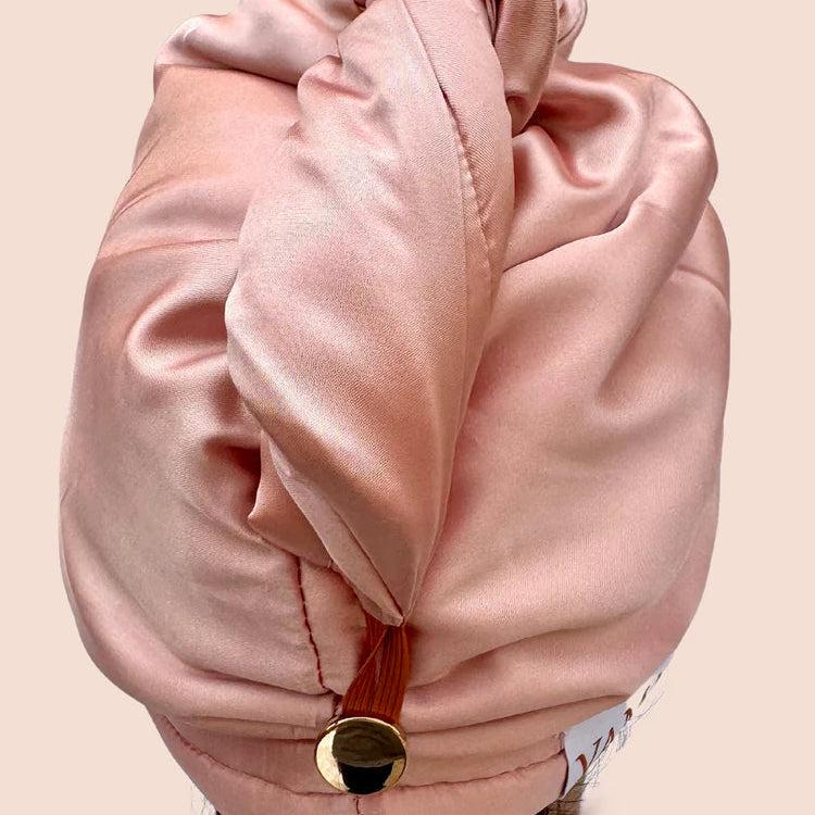 Pink satin headscarf with a gold button on a beige background