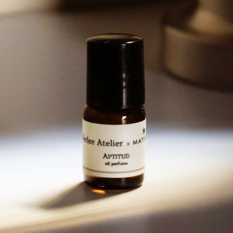 Small brown perfume bottle with a black cap on a white background