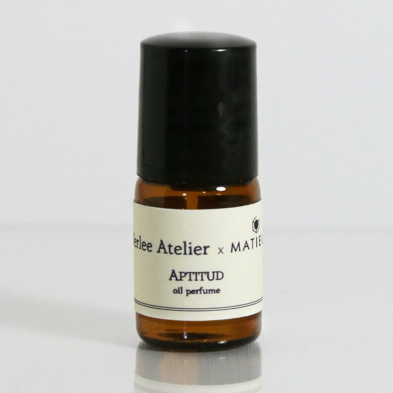 Small brown perfume bottle with a black cap on a light gray background