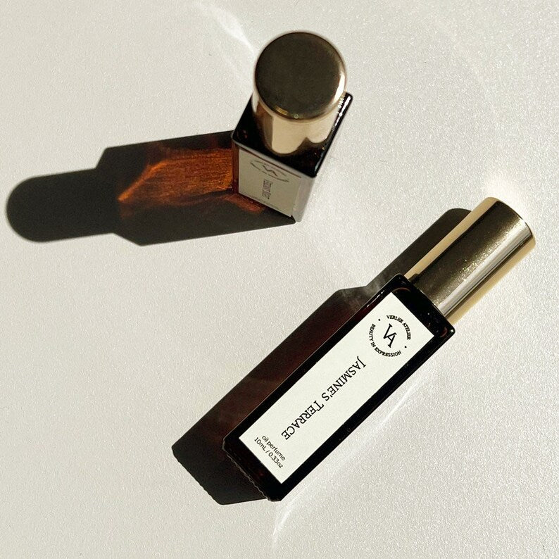 Two perfume bottles with gold caps on a light background