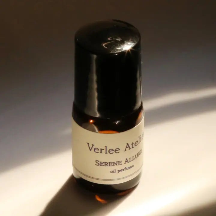 Bottle of Verlee Atelier Serene Allure oil perfume on a reflective surface with a dark background
