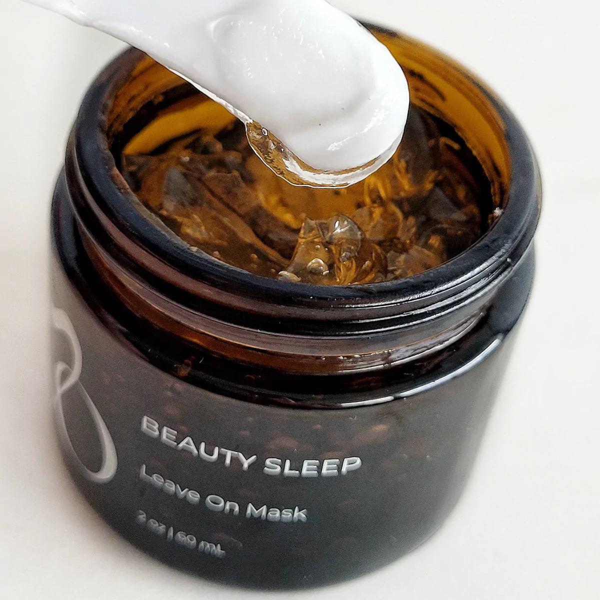 Jar of 'Beauty Sleep' leave-on mask with a white applicator on a light background