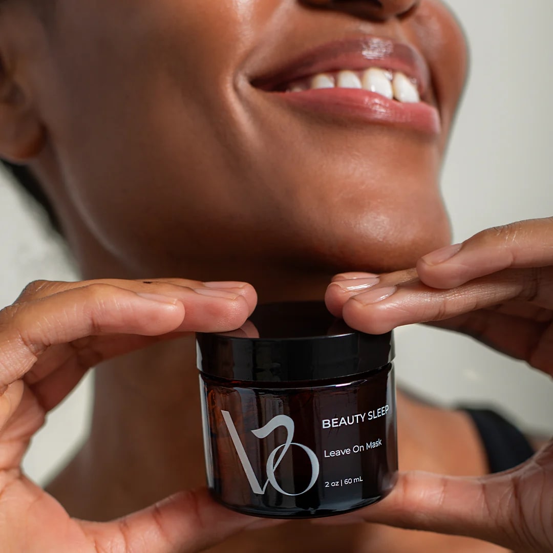 Person holding a jar of 'VO Beauty Sleep' leave-on mask with a blurred background