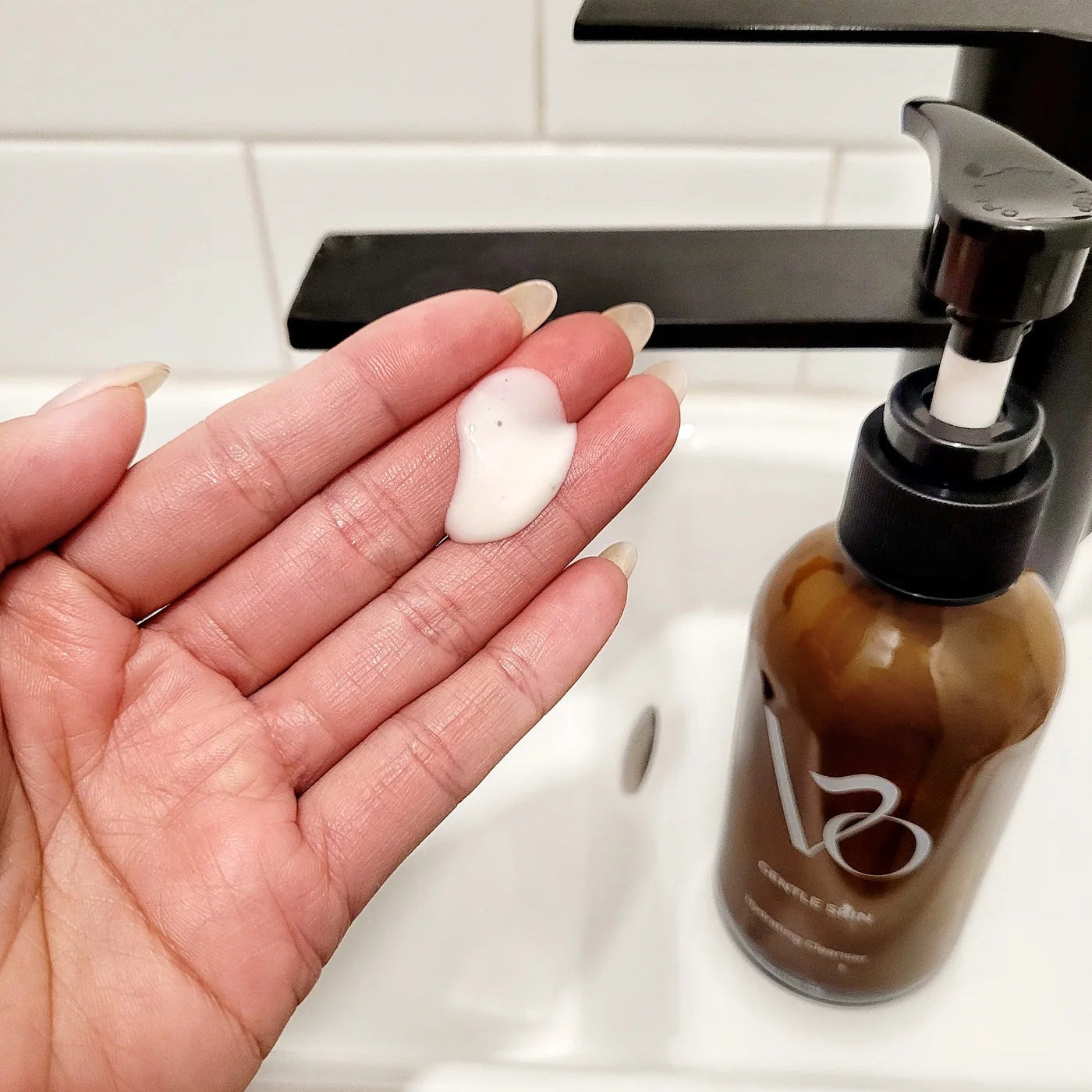 Hand holding a white bar of soap with a brown bottle labeled 'B2' in the background.