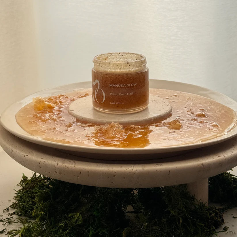 Jar of Manuka Glow product on a textured white stand with a natural background