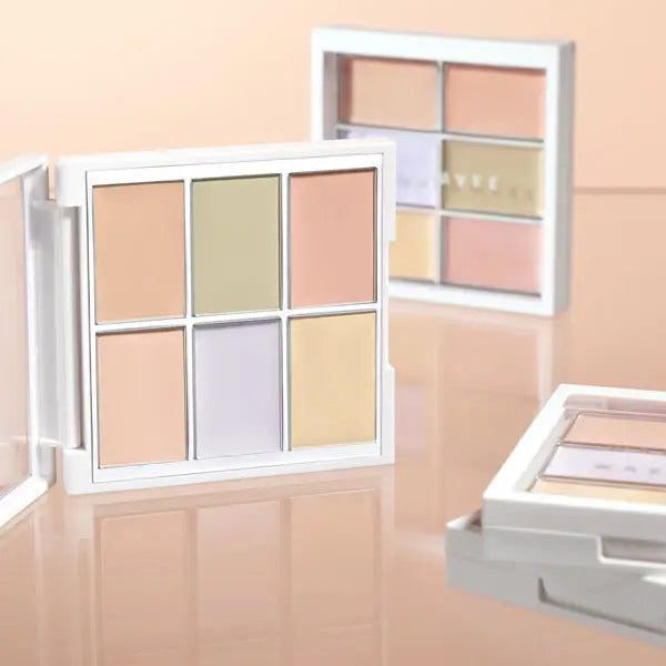 Makeup palette with various shades displayed in front of a window